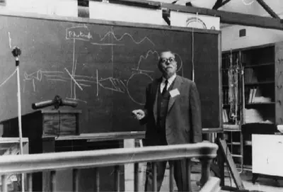 Wiener standing with chalk in hand before a blackboard with diagrams