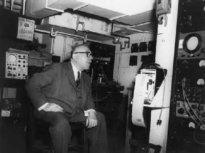 Wiener seated in an electronics laboratory surrounded by instruments