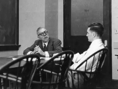 Wiener in conversation with a student across a table at MIT